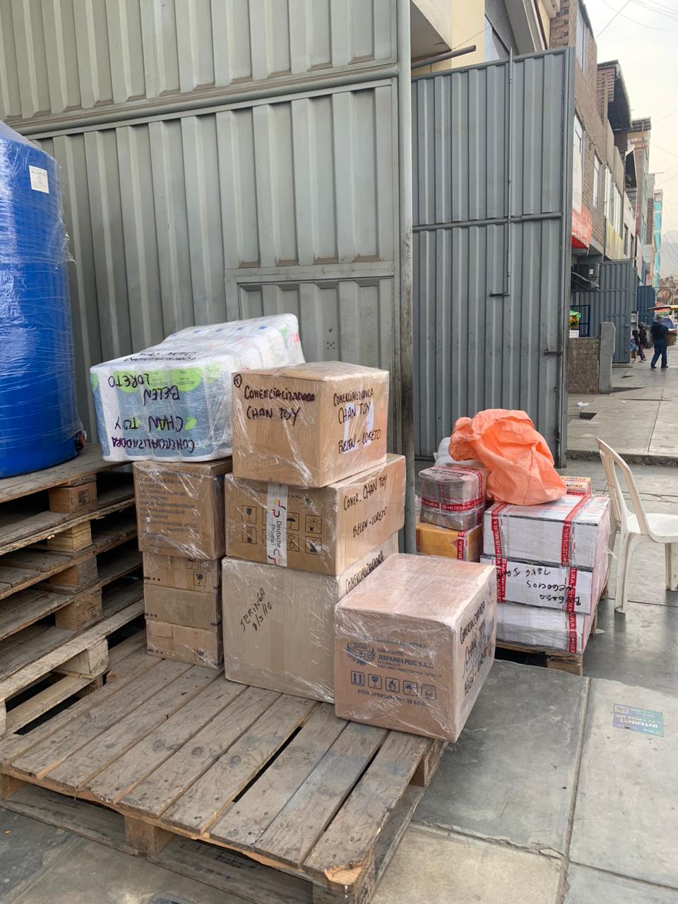 Cajas de pedidos mayoristas rotuladas por cliente, listas en agencia de transporte